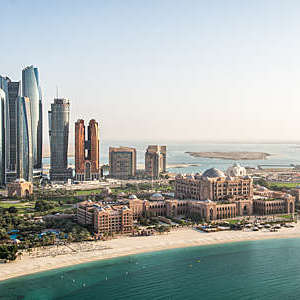 Aerial view of skyscrapers in Corniche bay in Abu Dhabi, UAE. Turquoise water in the front and blue sky in the distance combined with building exterior in the middle.
