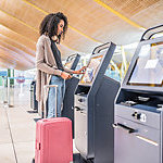 Woman using the check-in machine at the airport, getting the boarding pass.