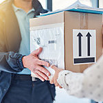 Cropped shot of the hands of a delivery man handing a package to a female customer.