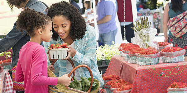 A mother and daughter take in the perfume of fresh strawberries at a local market.
