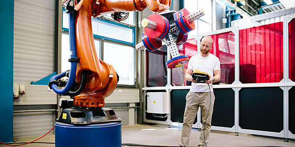 Engineer works a robotic arm from a tablet.