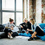Three businesswomen sitting on large Pillows in an office and  talking during an informal meeting