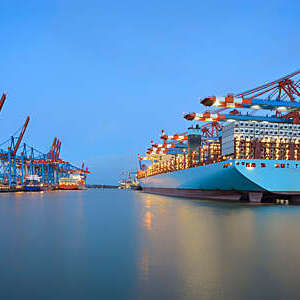 Cargo ship moored at a container terminal in the Port of Hamburg, Germany, at dawn.