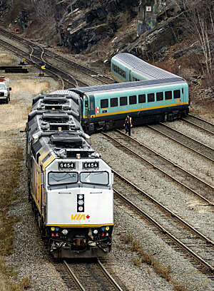 Workers of the Canadian National Railway, CN Rail, survey the damage to three coaches after a derailment.