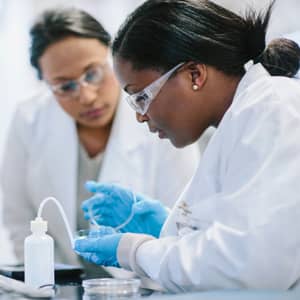 Female doctors examining petri dish in laboratory.