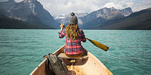 A young woman canoeing on a scenic mountain lake